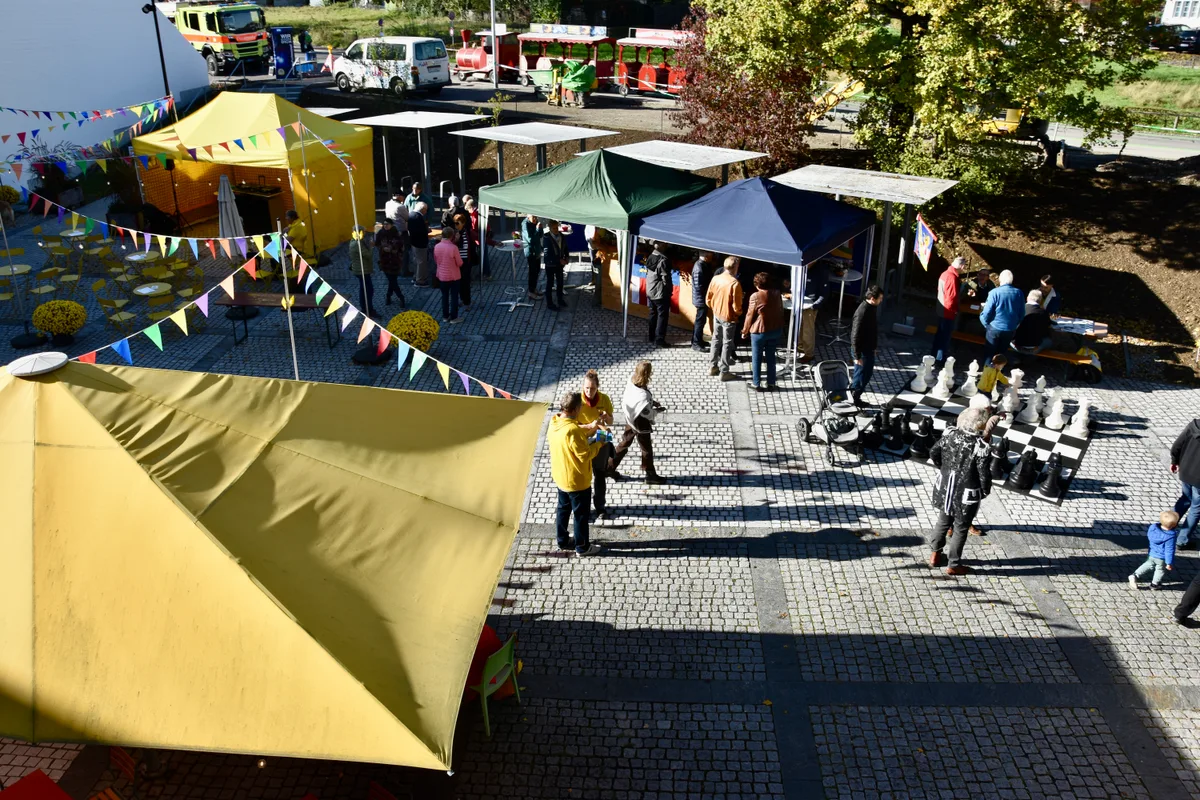 Auf dem Vorplatz konnten sich die Besucherinnen und Besucher über den Neubau austauschen.  Farbige Festzelte stehen auf einem Platz mit Pflastersteinen.